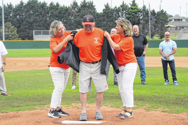 Former Post 52 Bat Girls Julie Ellison and Carol Jo Baumgardner help put the jacket on legendary coach Randy Bray on Friday night during the pregame ceremony at Gregg Powell Field. 
                                 Jeff Holt / The Easley Progress